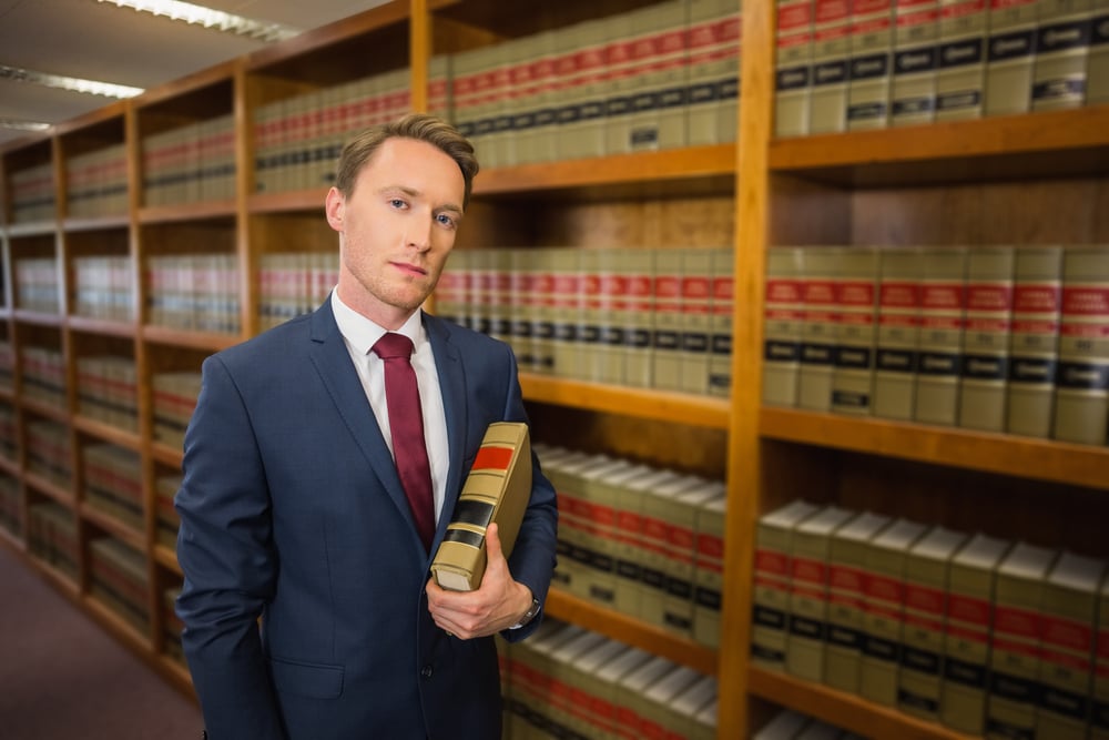 Professional lawyer reviewing property conveyancing documents in a law library.